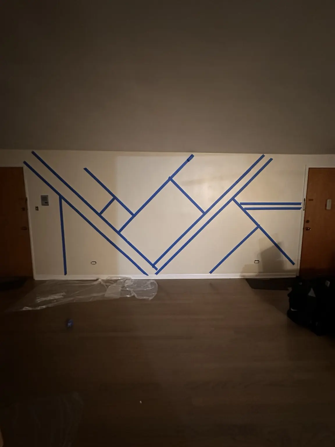 Blue painter's tape marking the geometric accent wall layout before trim installation